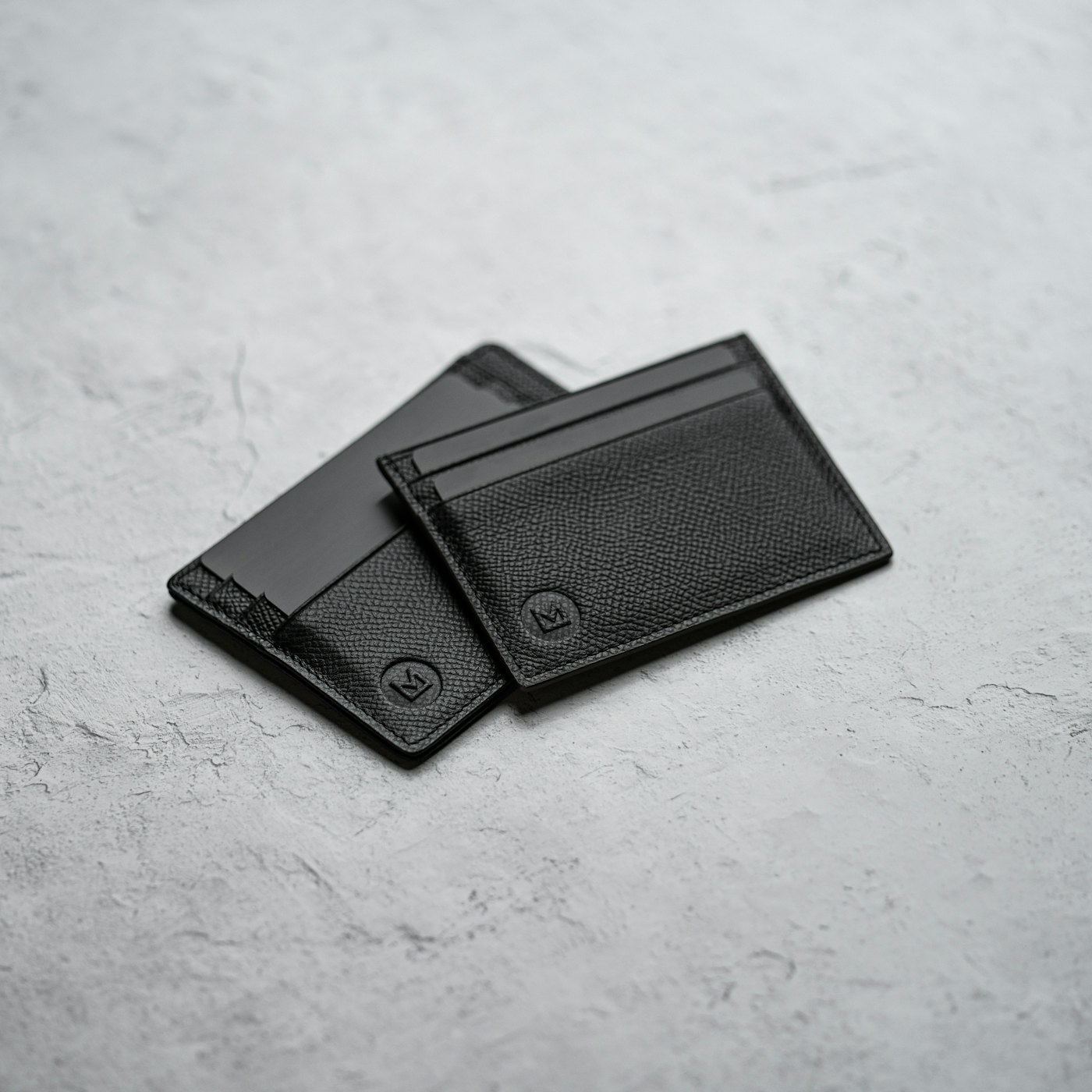 A slim black leather bifold wallet on a white surface