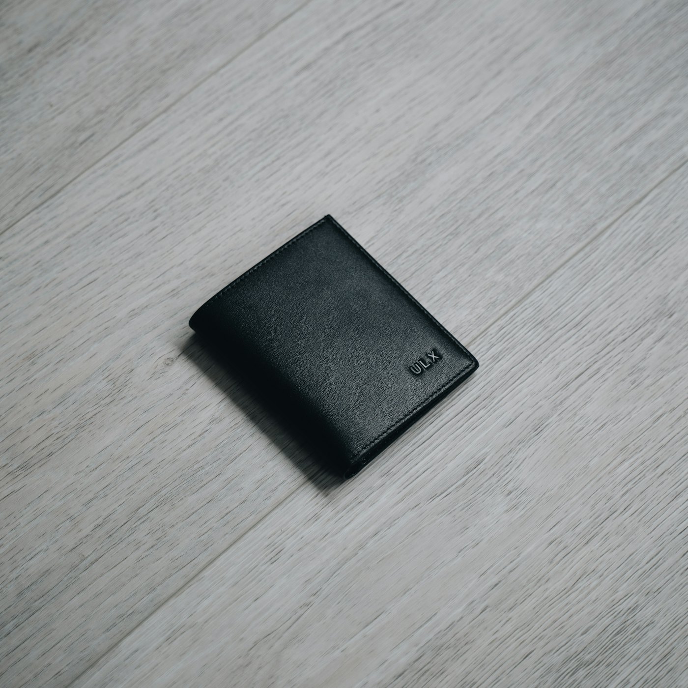 A black leather bifold wallet on a dark wooden table