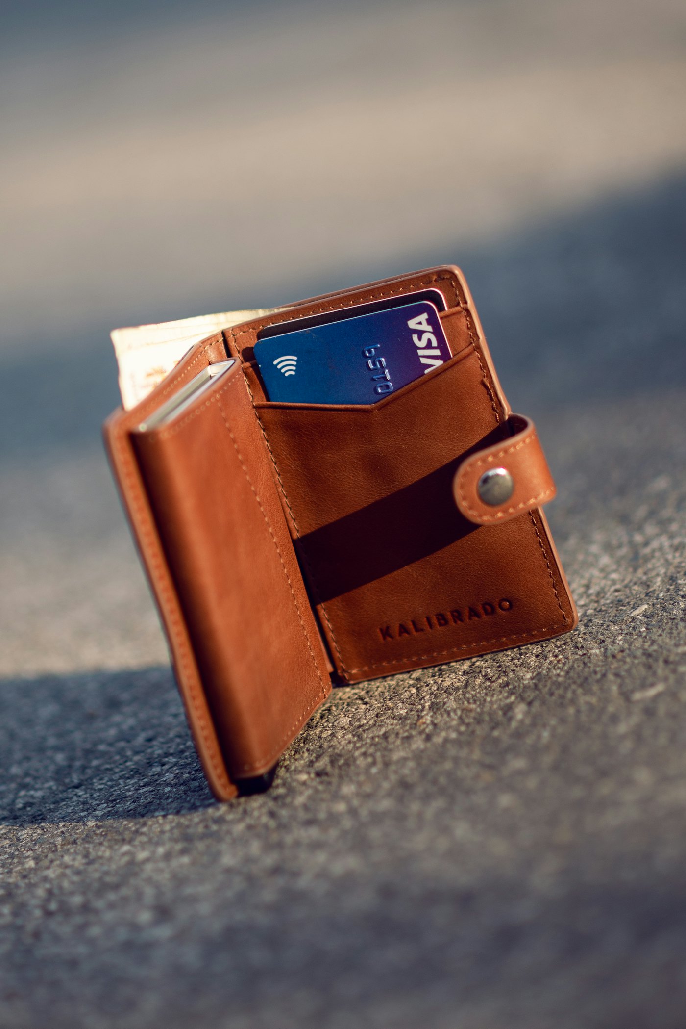 A brown leather bifold wallet on a grey concrete surface