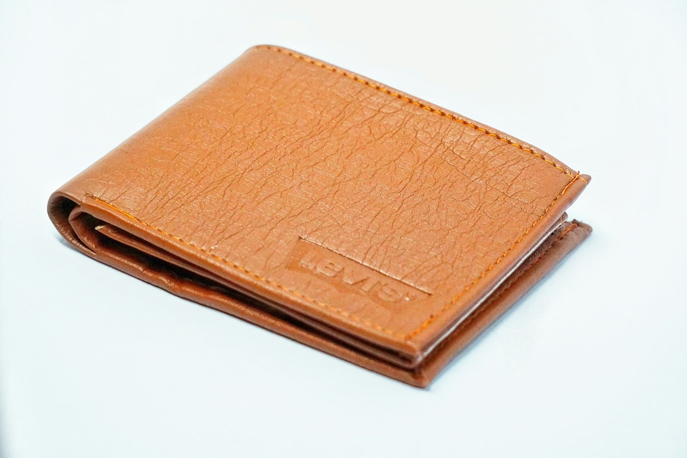 A brown leather bifold wallet open on a pale table