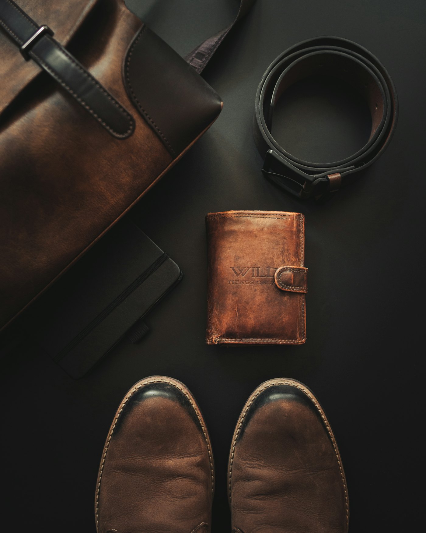 A wallet, belt and pair of shoes arranged on a table